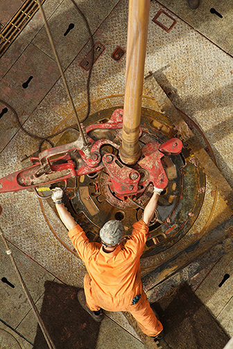 A drill operator working on the drilling floor on an oil rig